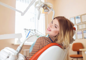 pretty woman in dentist chair wonders what is cosmetic dentistry