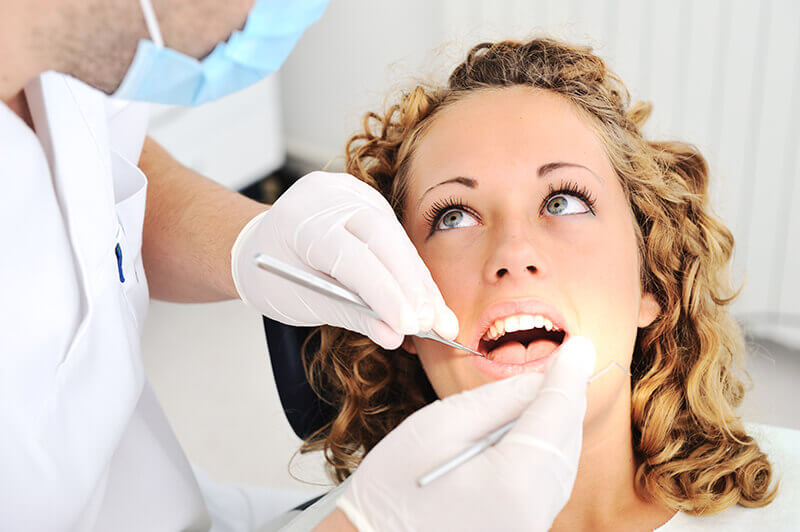 young woman looks at doctor performing cosmetic dentistry