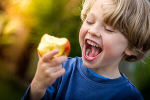 Kid eating an apple which is one of the healthy teeth foods for kids